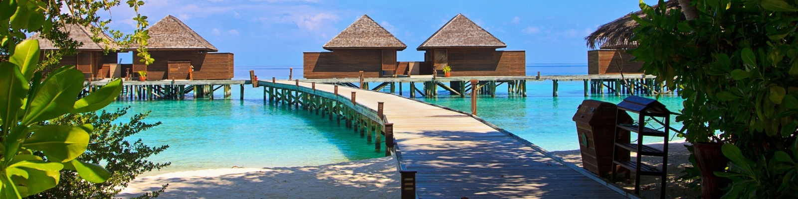 a wooden dock leading to two huts