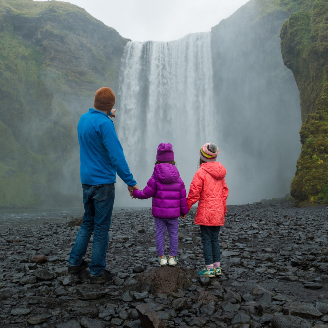 a man and two children standing in front of a waterfall